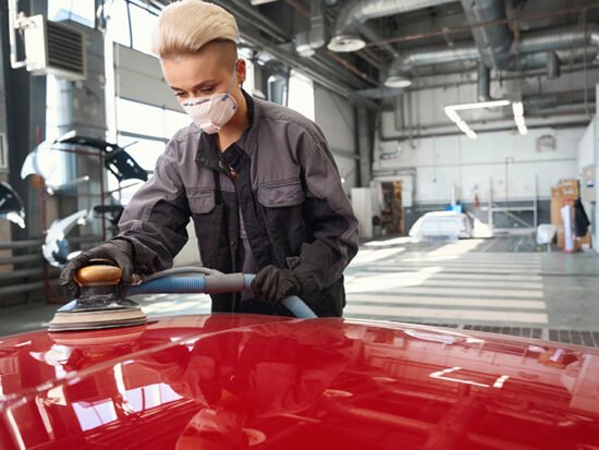 Worker sanding a car body