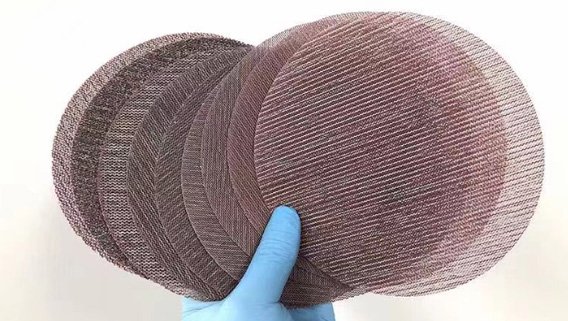 various grits of mesh abrasive discs being held by a gloved hand